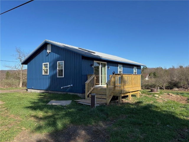 exterior space featuring a wooden deck, metal roof, and a front yard
