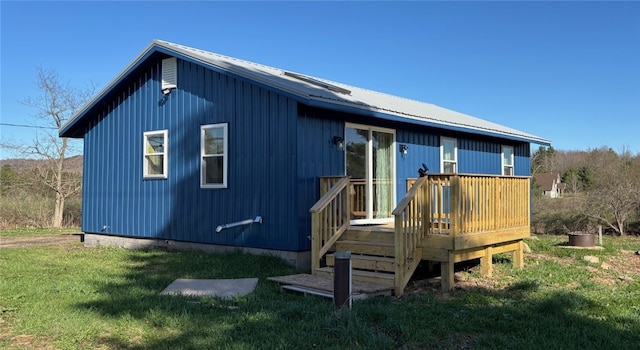 back of property featuring a yard, a deck, and metal roof