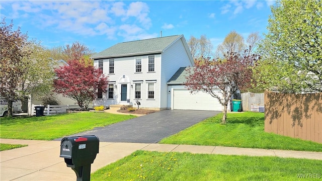 colonial-style house featuring a garage, aphalt driveway, fence, and a front yard