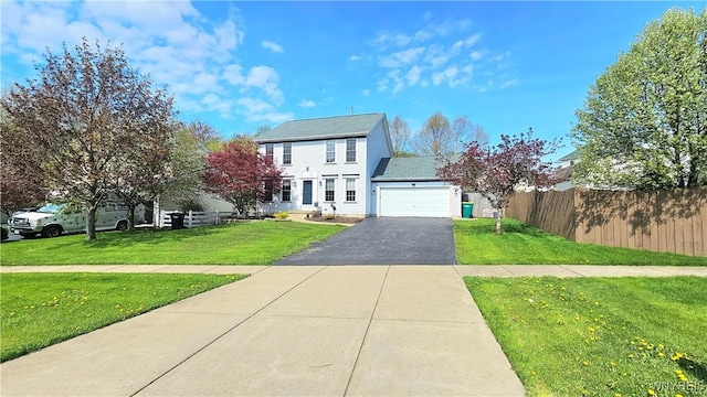 colonial inspired home featuring fence, an attached garage, a front lawn, and aphalt driveway
