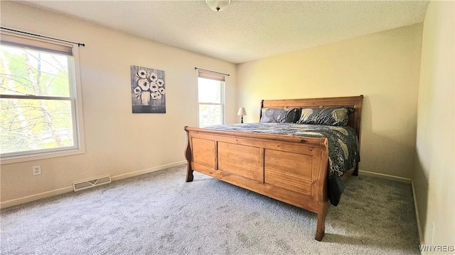bedroom with carpet floors, baseboards, a textured ceiling, and visible vents