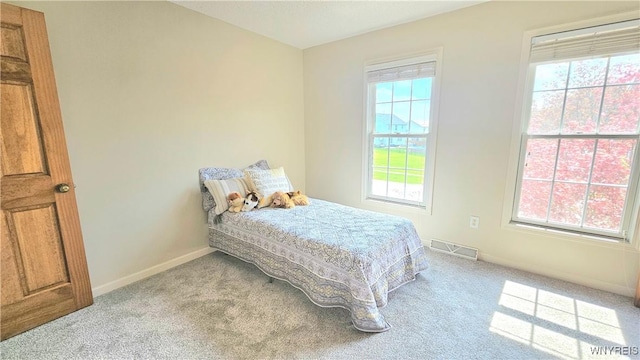 bedroom with light colored carpet, multiple windows, and visible vents
