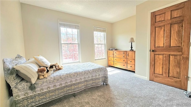 bedroom featuring baseboards, light carpet, and a textured ceiling