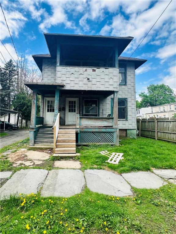 view of front of house with a front lawn, a balcony, fence, and covered porch