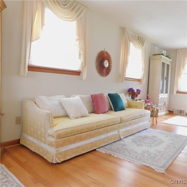 living room featuring baseboards, wood finished floors, and visible vents