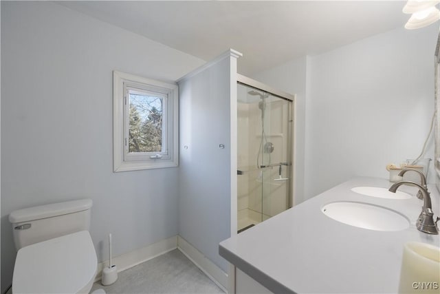 bathroom featuring a sink, a shower stall, toilet, and double vanity