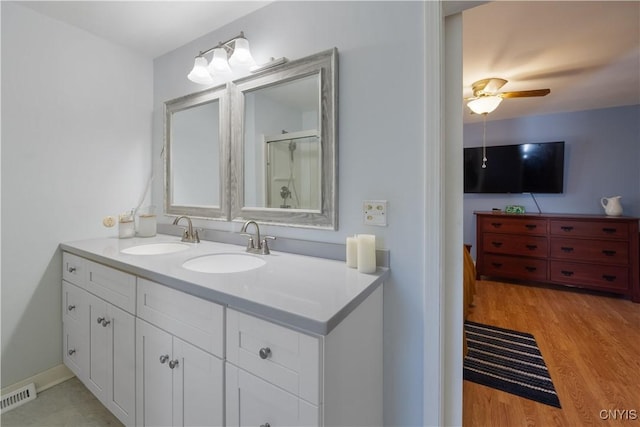 bathroom featuring a sink, double vanity, wood finished floors, and visible vents