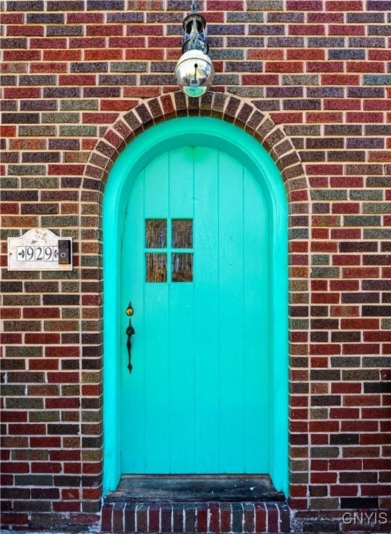 doorway to property featuring brick siding
