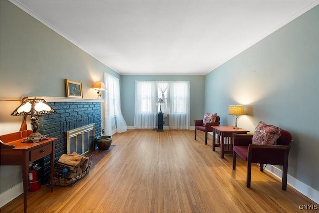 sitting room featuring baseboards, a brick fireplace, and wood finished floors