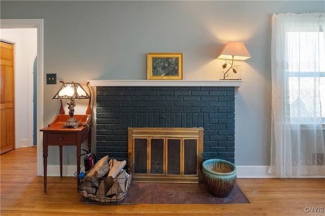 interior space with a fire extinguisher, baseboards, a fireplace, and wood finished floors