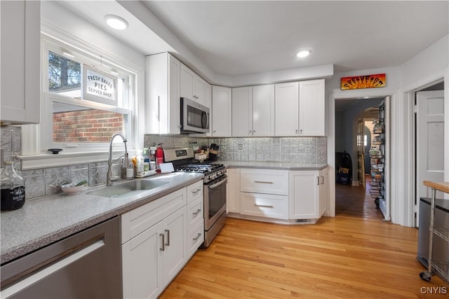kitchen with a sink, decorative backsplash, white cabinets, and stainless steel appliances