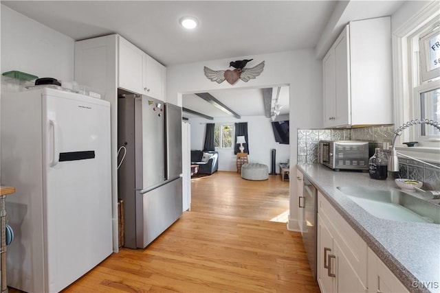 kitchen with light wood-style floors, a sink, white cabinetry, and stainless steel appliances