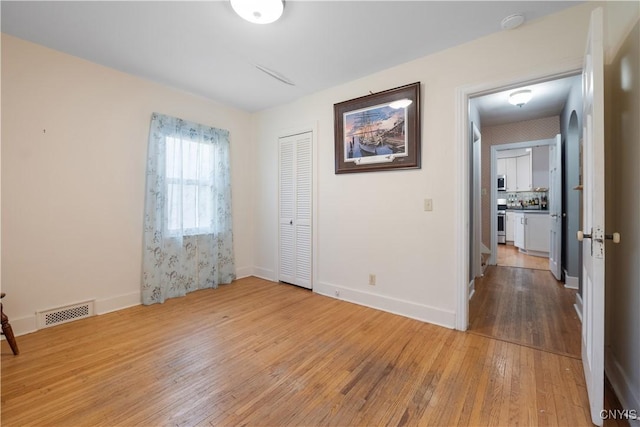 unfurnished room featuring wood-type flooring, baseboards, and visible vents