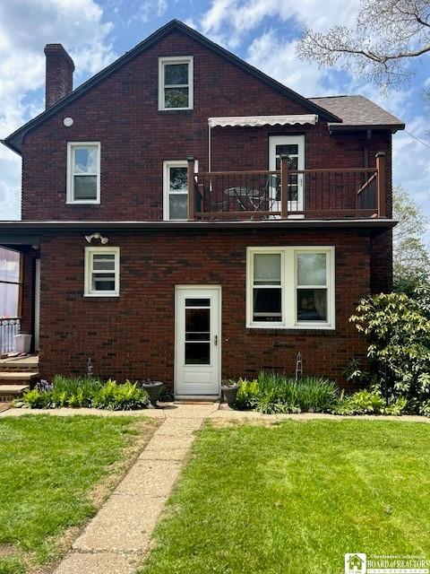 4 Brewer Pl, Westfield, NY 14787 - view of front of home featuring brick siding, a chimney, a balcony, and a front lawn
