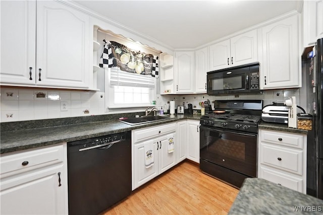 kitchen featuring white cabinets, dark countertops, a sink, and black appliances