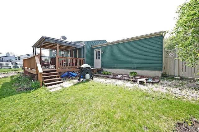 back of property featuring fence, a wooden deck, and a yard