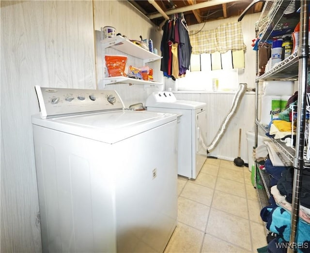 clothes washing area featuring washer and dryer, light tile patterned flooring, and laundry area