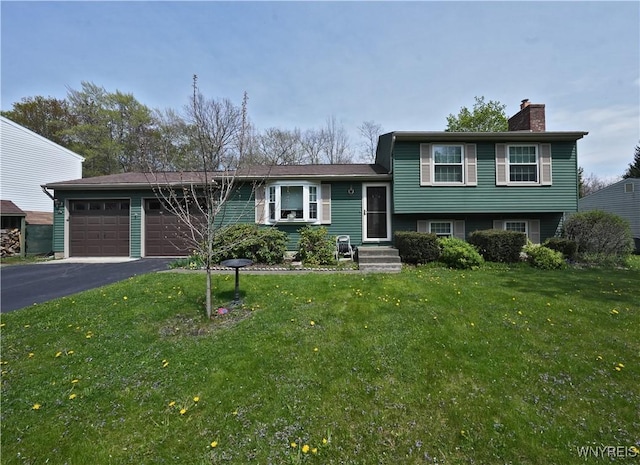 split level home featuring a garage, aphalt driveway, a front yard, and a chimney