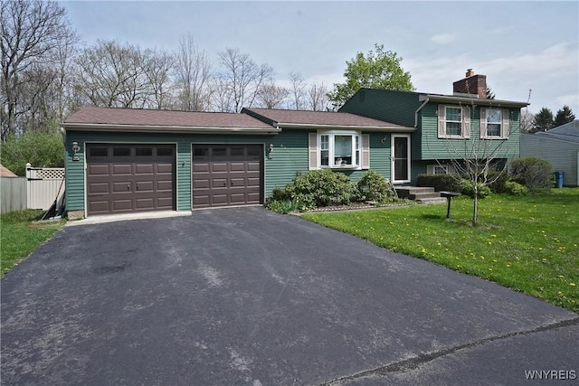 split level home with a garage, a front lawn, driveway, and a chimney