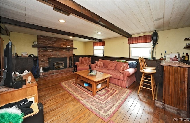 living room with visible vents, bar area, hardwood / wood-style floors, and beamed ceiling