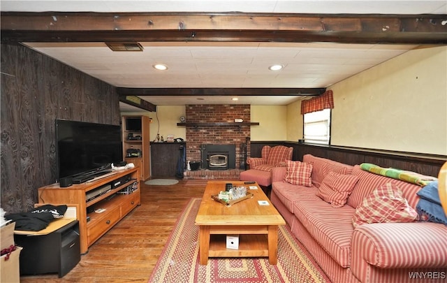 living room featuring recessed lighting, beamed ceiling, wood walls, and light wood finished floors