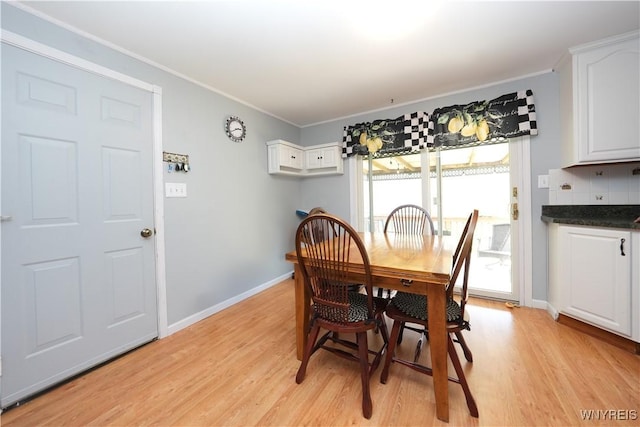 dining area with baseboards, ornamental molding, and light wood-type flooring