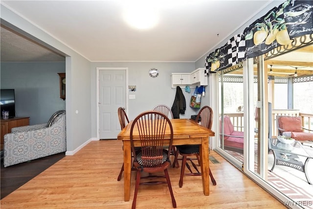 dining space featuring light wood-style floors, baseboards, and crown molding