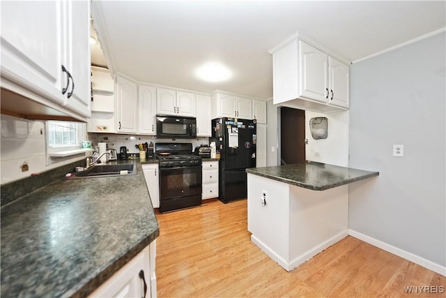 kitchen with a peninsula, dark countertops, a sink, and black appliances