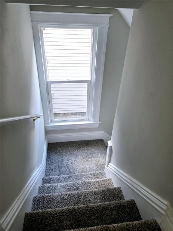 staircase featuring baseboards, carpet flooring, and lofted ceiling