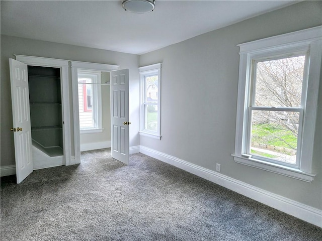 unfurnished bedroom with carpet flooring, baseboards, and multiple windows