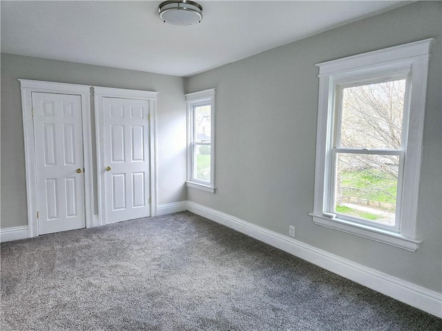 unfurnished bedroom featuring baseboards, multiple windows, and carpet flooring