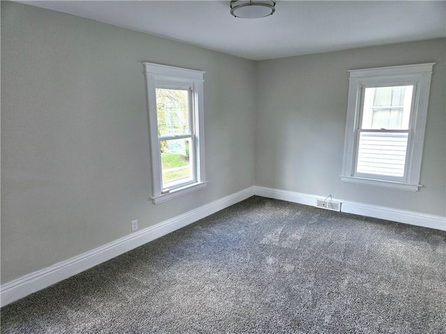 unfurnished room featuring dark colored carpet, baseboards, and visible vents