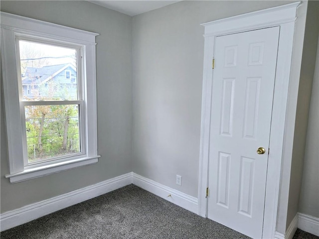 empty room featuring baseboards and dark colored carpet