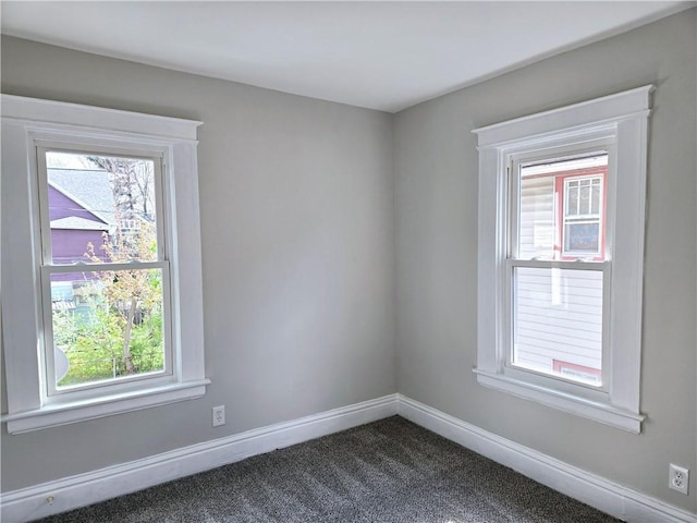 unfurnished room with baseboards and dark colored carpet