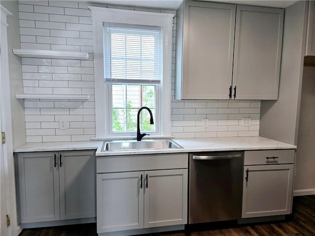 kitchen featuring stainless steel dishwasher, dark wood-style floors, tasteful backsplash, a sink, and gray cabinetry