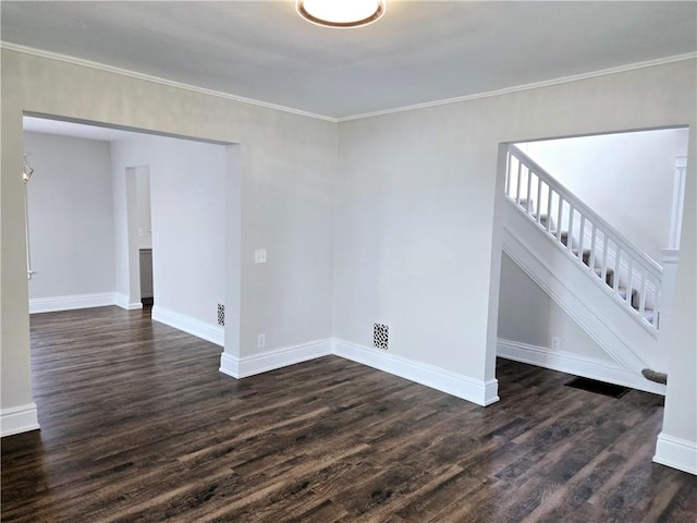 empty room featuring baseboards, dark wood-style floors, and stairway
