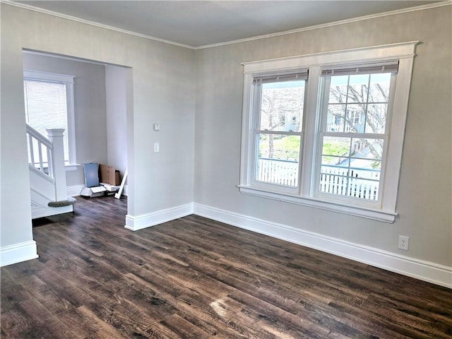unfurnished room with crown molding, baseboards, dark wood finished floors, and stairs