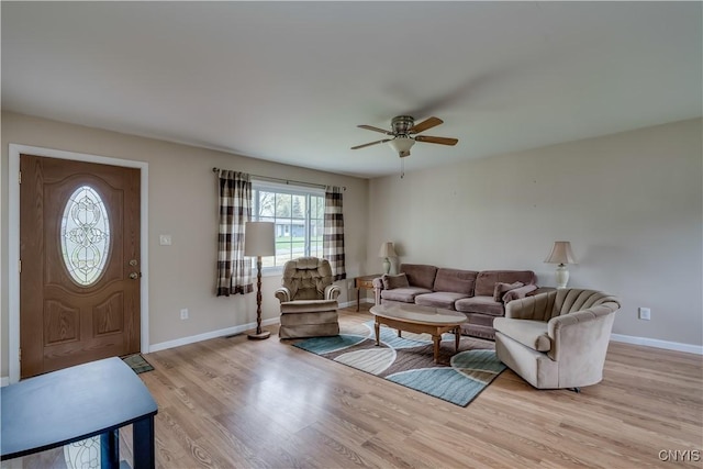 living area featuring baseboards, a ceiling fan, and light wood-type flooring