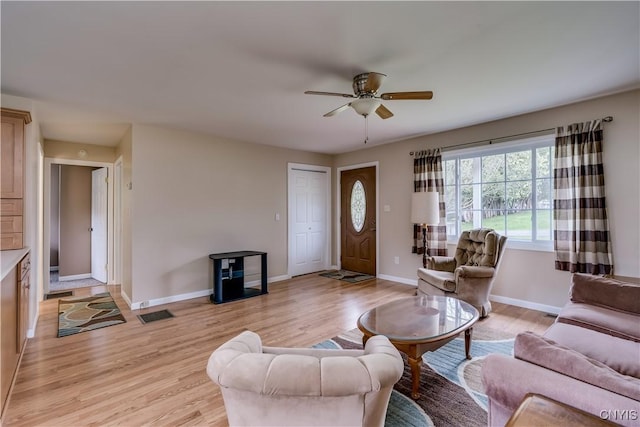 living room featuring light wood-type flooring, baseboards, ceiling fan, and visible vents