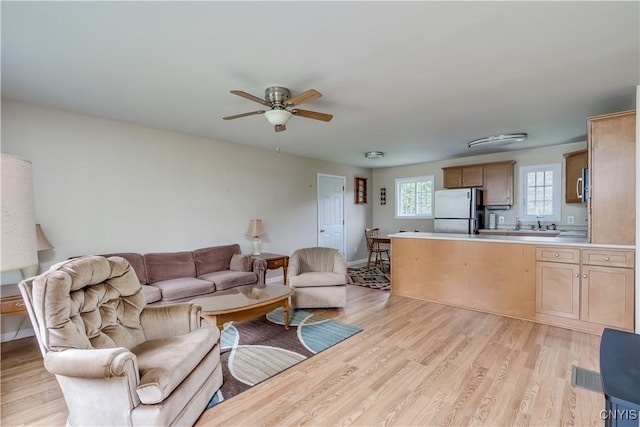 living area featuring a ceiling fan and light wood finished floors