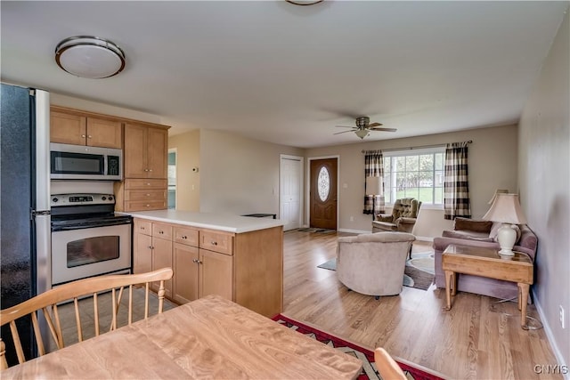 kitchen with light wood-style floors, light countertops, stainless steel appliances, open floor plan, and a ceiling fan