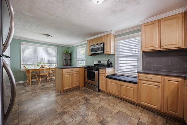 kitchen featuring dark countertops, stainless steel appliances, a peninsula, stone finish flooring, and decorative backsplash
