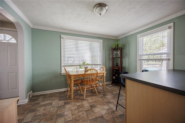 dining room featuring arched walkways, plenty of natural light, and ornamental molding