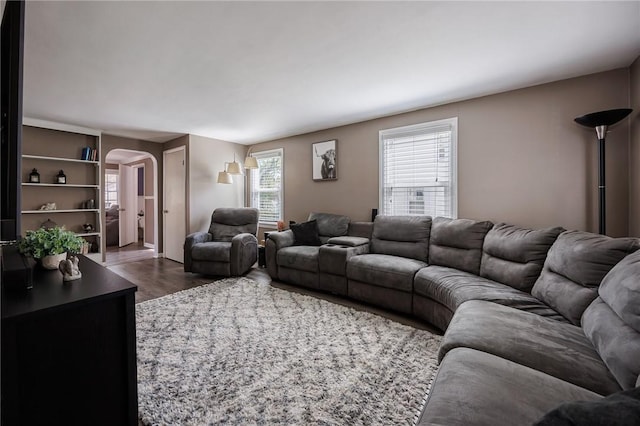 living area featuring arched walkways and dark wood-style flooring
