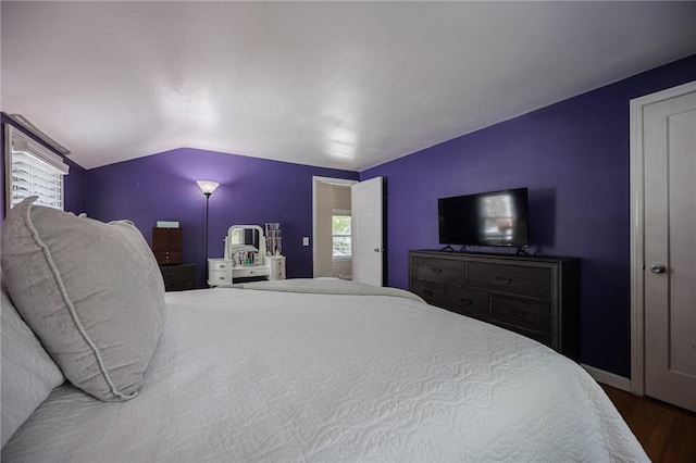 bedroom featuring baseboards, lofted ceiling, and wood finished floors