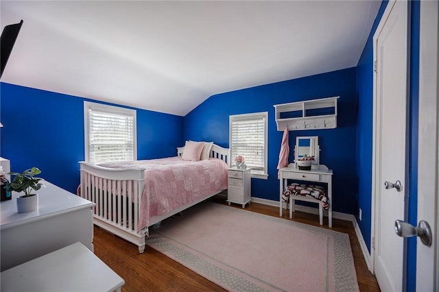 bedroom with baseboards, multiple windows, vaulted ceiling, and wood finished floors