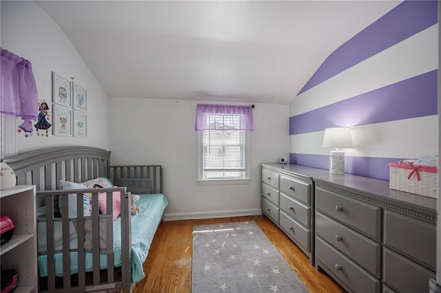 bedroom with baseboards, light wood finished floors, and lofted ceiling