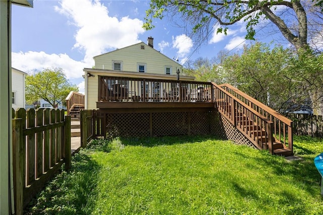 back of property with a wooden deck, stairway, a fenced backyard, a chimney, and a lawn