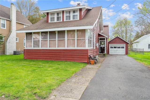bungalow-style house featuring central AC, a front lawn, aphalt driveway, a detached garage, and an outbuilding