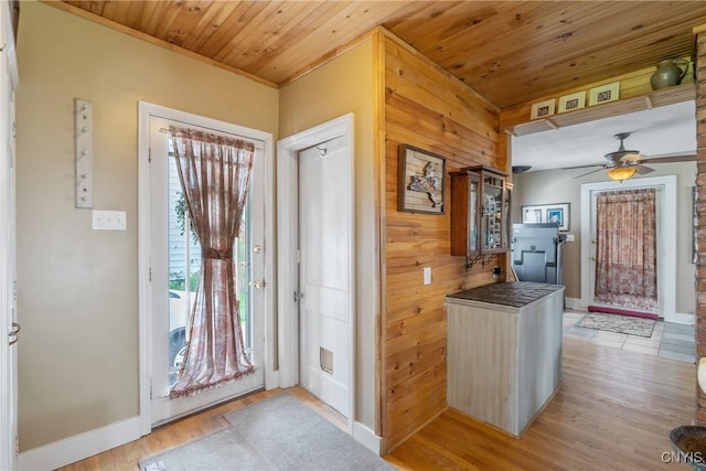 entryway featuring crown molding, baseboards, light wood-style floors, wood ceiling, and a ceiling fan